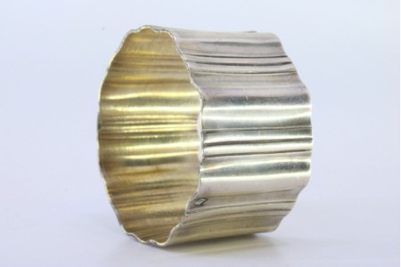  Argola de guardanapo em prata com faixas lisas e caneladas em forma ondeada.